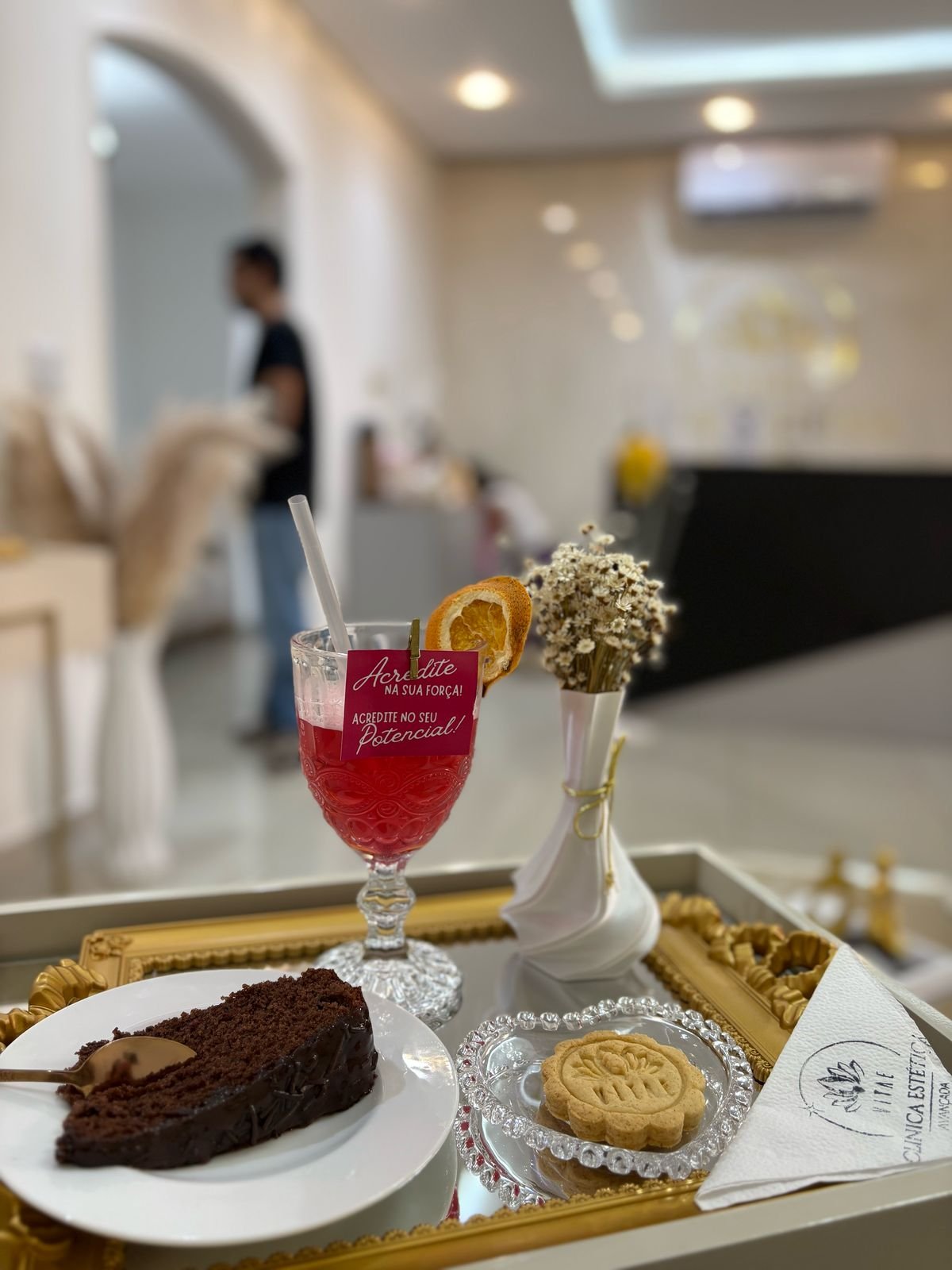 Detalhe de acolhimento na recepção oficial da Vitae, com bebida e flores sobre uma bandeja.